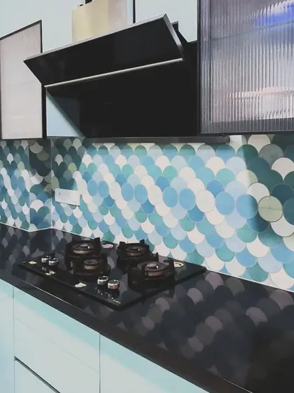 The cooking area of the pastel blue kitchen, featuring a four-burner hob on a black granite countertop. The fluted glass on the upper cabinets adds a touch of texture and elegance to the colorful design.