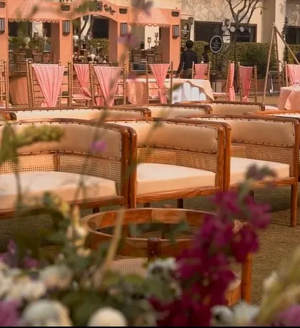 The guest seating area, featuring elegant wooden benches that complement the natural, outdoor setting. The decor is kept consistent with pink drapes and floral arrangements in the background.