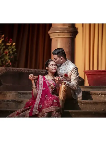 An intimate moment during a pre-wedding shoot in a palace-like setting, where the groom gently kisses the bride's forehead.