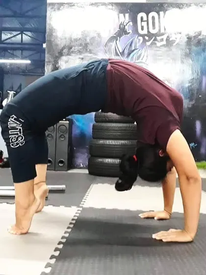 A student holds a strong wheel pose (Chakrasana) on their toes, which increases the intensity of the backbend and engages the leg muscles more deeply.