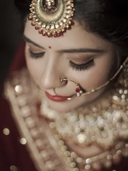 An artistic close-up with a shallow depth of field, focusing on the bride's eyes and nose ring, with the background dissolving into soft bokeh.