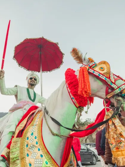 A low-angle shot capturing the groom's regal presence on the decorated horse, holding a sword, ready to claim his bride.