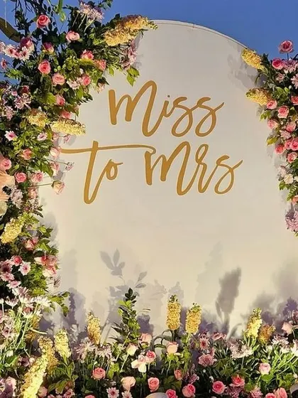 A lovely "Miss to Mrs" photo backdrop for a bridal shower or Mehendi. The circular white board is framed with a beautiful arrangement of pastel flowers.