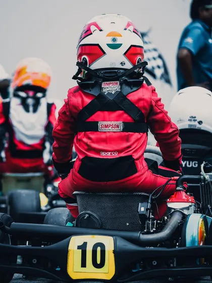 A young driver in his race suit, seen from behind.
