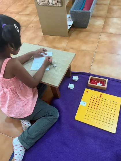 A child works on a multiplication board, a hands-on tool that makes the abstract concept of multiplication tangible and easy to understand.