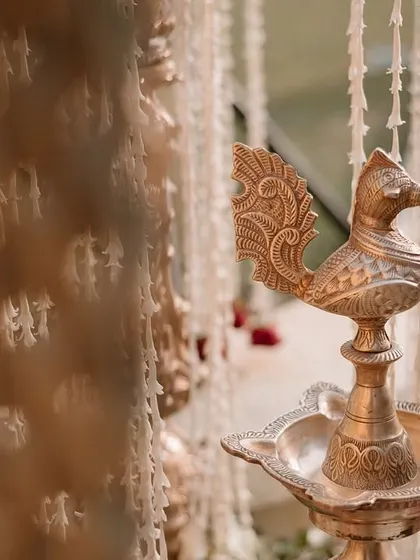 A close-up of a traditional brass 'Samai' or oil lamp, an auspicious element in Indian ceremonies.