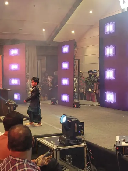 A young participant on the LED stage during the children's ramp walk event. The illuminated stage creates a high-energy, professional fashion show experience.