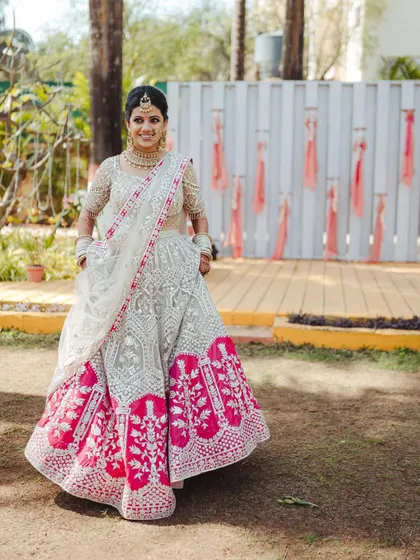 A full-length shot of the bride, showing off her stunning white and pink lehenga in all its glory.