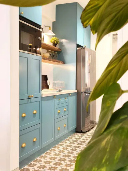 A detail shot of the Breeze Home kitchen, showing the beautiful color of the custom cabinetry. The color was inspired by the patterned floor tiles, and the open wooden shelves add warmth and a place to display personal items.