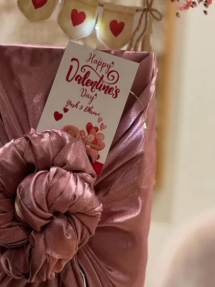 A gift wrapped in dusty rose fabric using the Furoshiki technique, complete with a personalized Valentine's Day card.