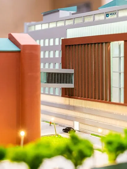 A close-up of the Max Hospital Mohali model shows the sky bridge connecting the new and old blocks. A terracotta dry-clad facade reinterprets the original brick structure, creating a cohesive yet contemporary identity.