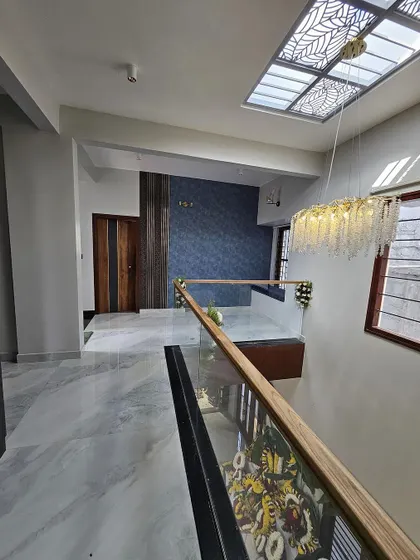 The interior of a contemporary villa we designed, featuring a stunning double-height ceiling with a skylight, a modern chandelier, and a glass-railing staircase.