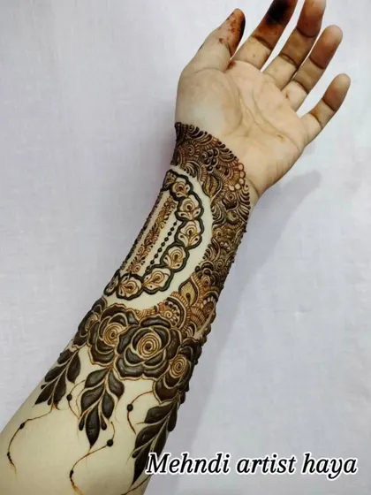 A unique design featuring a decorative cuff on the forearm, complemented by a trail of roses. The use of negative space makes the artwork pop.
