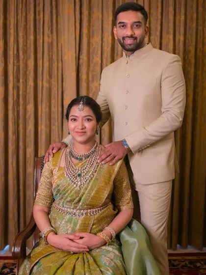 This couple looks absolutely radiant. The mom-to-be is wearing a custom green embroidered blouse with her Kanchivaram saree, and her husband is in a classic cream bandhgala.