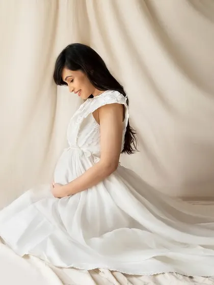 Kneeling in a flowing white gown against a draped beige backdrop. This pose creates a lovely, gentle silhouette that is both humble and powerful.