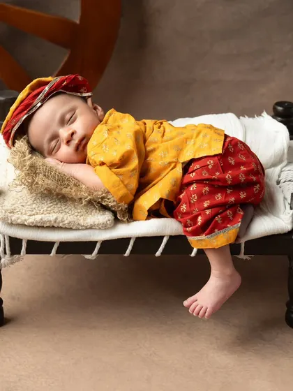 A vintage soul. This Rajasthani-themed newborn shoot features traditional clothing and a miniature cot.