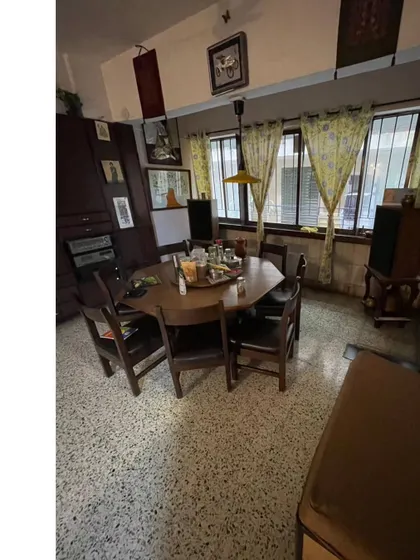 **BEFORE:** The original dining and family lounge area, characterized by dark furniture, cluttered storage, and dated decor.