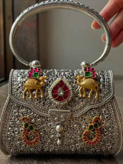 An example of my detailed craftsmanship on a pure silver clutch. This piece features intricate filigree work and is adorned with custom motifs, including gold-plated camels and colourful Kundan work, making it a true statement accessory.