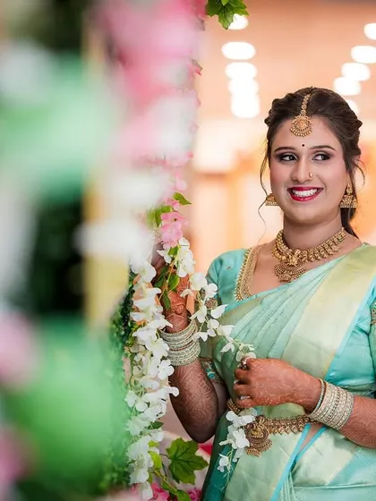 A candid shot of the bride in a lovely pastel blue saree, smiling as she interacts with the floral decor.