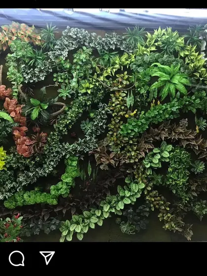 This is a highly-textured green wall with a wide variety of artificial plants, including ferns and colorful foliage. This style is great for creating a focal point that feels like a piece of living art.