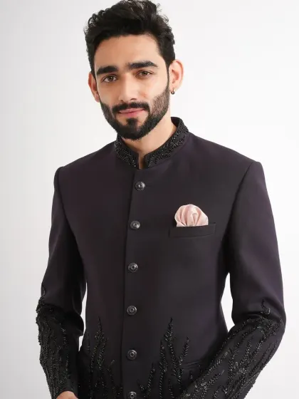 A dark purple Jodhpuri suit with black beadwork on the cuffs and collar. The subtle embellishment adds texture and a modern edge.