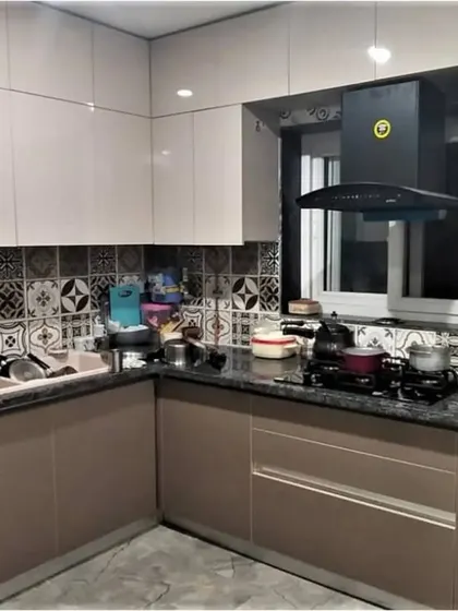 A practical and stylish kitchen featuring beige cabinets, a black granite countertop, and a decorative tiled backsplash. This design is perfect for everyday use while maintaining a clean and organized look.