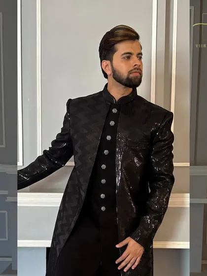 A close-up of the textured, sequined fabric on our black Indo-Western sherwani. The detail in the fabric itself makes a statement.