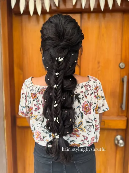 A voluminous pull-through braid decorated with baby's breath. This technique creates the illusion of a much thicker braid and is a popular choice for festive occasions.