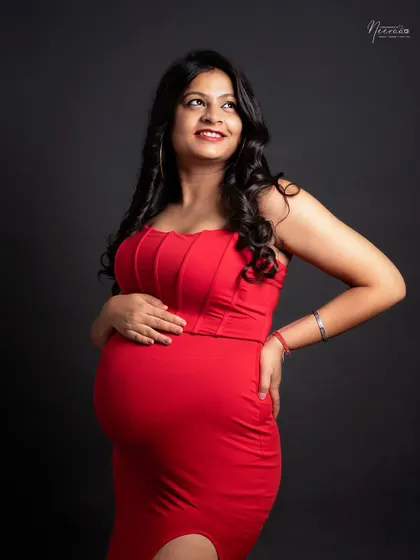A joyful and candid moment. Her upward glance and bright smile capture the pure happiness and excitement of waiting to meet her baby.