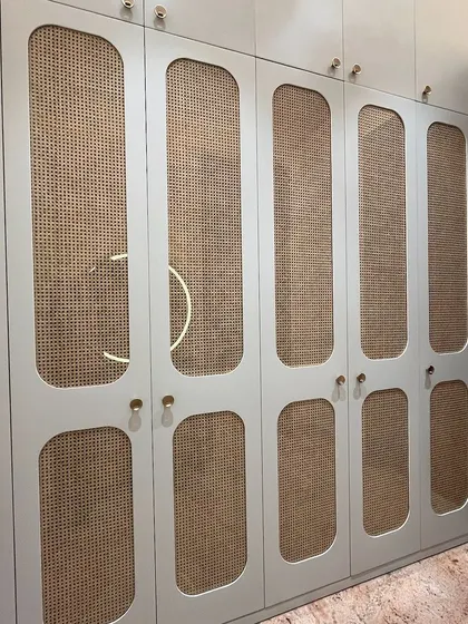For this wardrobe in a parent's room, we used natural rattan panels set within PU-finished doors. This blend of materials adds a touch of timeless elegance and texture to the storage unit.