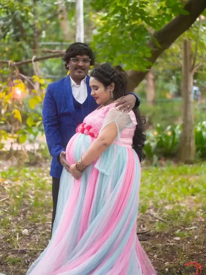 This rainbow-colored gown is a fun and vibrant choice for a maternity shoot, paired here with a stylish blue suit for the partner.