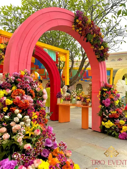 A stunning entrance for a Mehendi ceremony, with colorful floral arches creating a pathway of blooms for guests to walk through.