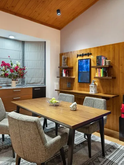 The dining area is wrapped in warmth, featuring a custom dining table made from reclaimed wood. Framed by a large bay window, the space offers views of Kasauli’s changing skies and includes a bespoke buffet unit for showcasing local artifacts.