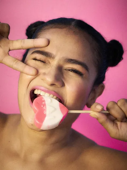 Playful and edgy, this shot with a heart-shaped lollipop against a vibrant pink background is perfect for a youth-focused brand or confectionery product.
