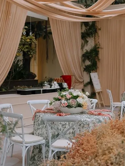 A quiet corner of the event, where guests can relax amidst tables dressed in floral linens and surrounded by walls of preserved botanicals.