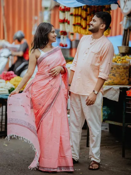 A lovely portrait of the couple standing in the flower market, the bride holding her pink saree, surrounded by garlands of marigolds.
