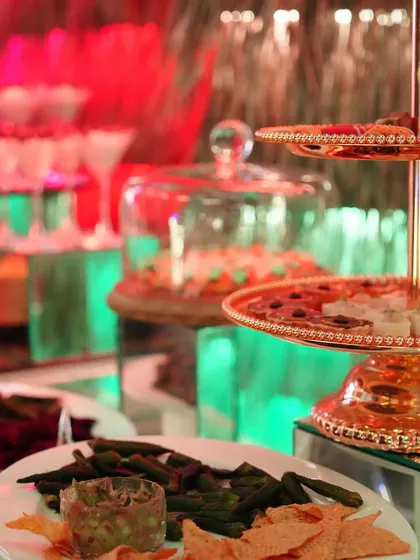 A dessert buffet with a variety of treats, including rose panna cotta and other small bites, set against a colourful, illuminated backdrop.