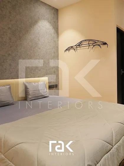 This bedroom features a textured grey accent wall and a unique wireframe car sculpture, reflecting a modern and personal style. The design is minimalist yet full of character.