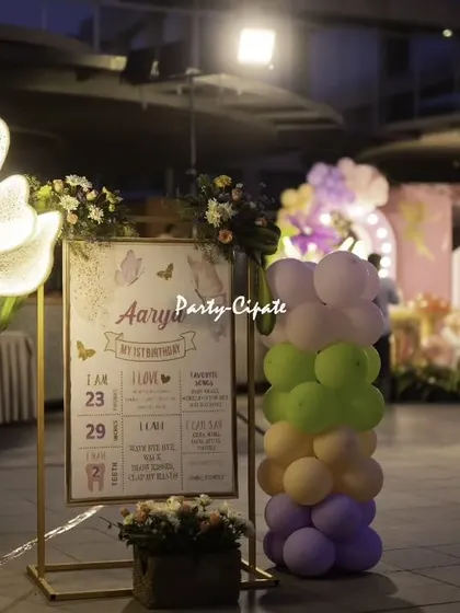 A personalized milestone board for Aarya's first birthday, set next to a glowing flower lamp. It's a wonderful way to share the baby's journey over their first year with friends and family.