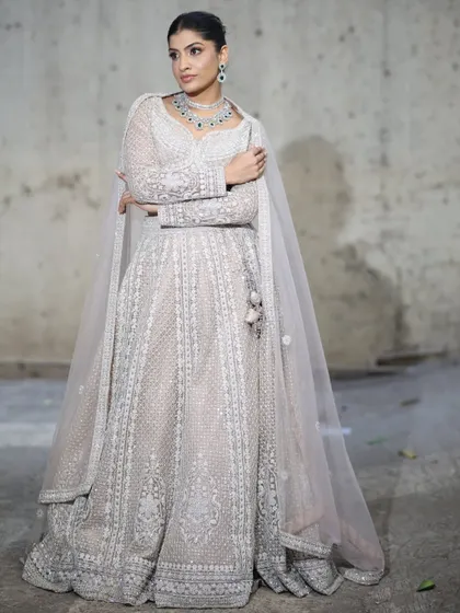 An elegant, full-length Anarkali-style gown in a subtle off-white. This rental is perfect for a sophisticated reception or engagement party look.