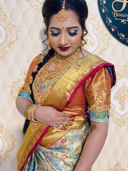 A stunning South Indian bridal look. This features a rich Kanjeevaram saree, heavy temple jewellery, and bold makeup with blue-toned eyeshadow and a deep red lip.