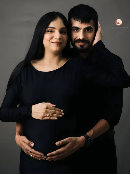 A warm and loving portrait of the couple. The partner embraces his wife from behind, both looking at the camera with gentle smiles, showcasing their unity.