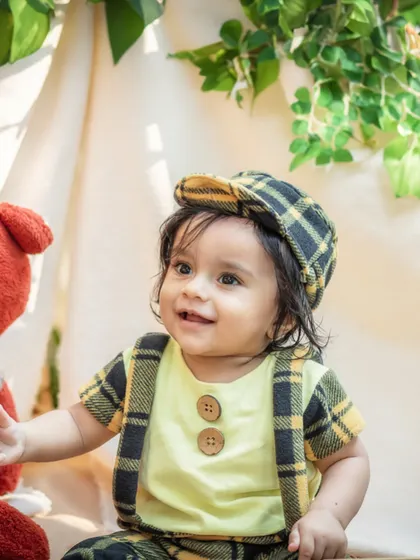 A dapper little gentleman in his plaid outfit, smiling brightly during his outdoor milestone session. The natural light makes his happy expression shine.