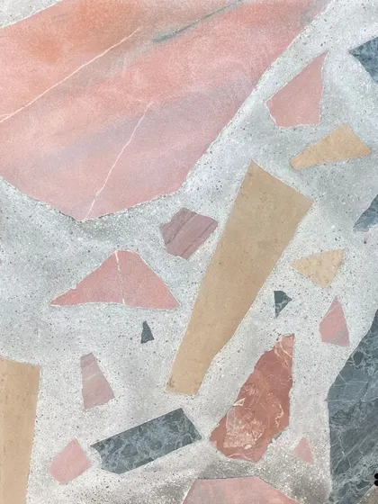A close-up of a beautiful Venetian terrazzo with large chunks of Indian natural stone in pink, beige, and grey. This style creates a bold, geological look.