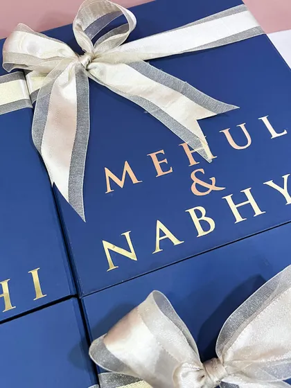 Another angle of the personalized groomsmen boxes, showing the names of the couple, "Mehul & Nabhya," on one of the gifts.