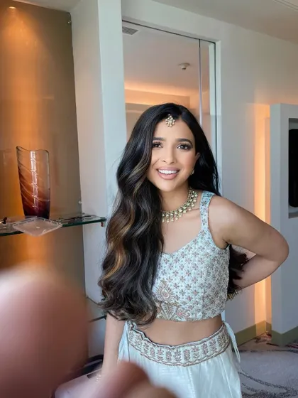 A simple open hairstyle with a center part and soft waves. The look is elevated with a small maang tikka, making it perfect for a pre wedding event.