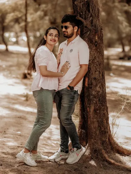A quiet, romantic moment shared between a couple leaning against a tree, the warm tones of the photo adding to the intimate feel.