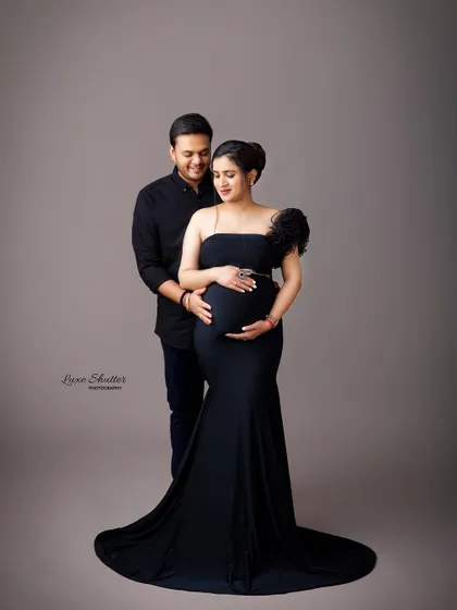 A full-length formal portrait of the couple in elegant black attire. This is a timeless and sophisticated way to document your pregnancy journey together.