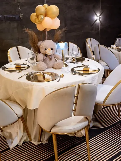 The guest tables at the elegant teddy bear party were beautifully set with gold chargers and a teddy bear centerpiece. The modern chairs with gold accents complemented the sophisticated look.