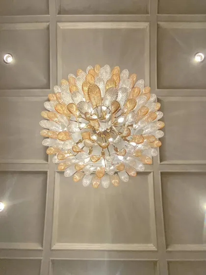 A look up at the custom chandelier in the Bhopal project. This intricate light fixture acts as a centerpiece, drawing the eye upward and adding a sculptural element to the coffered ceiling.